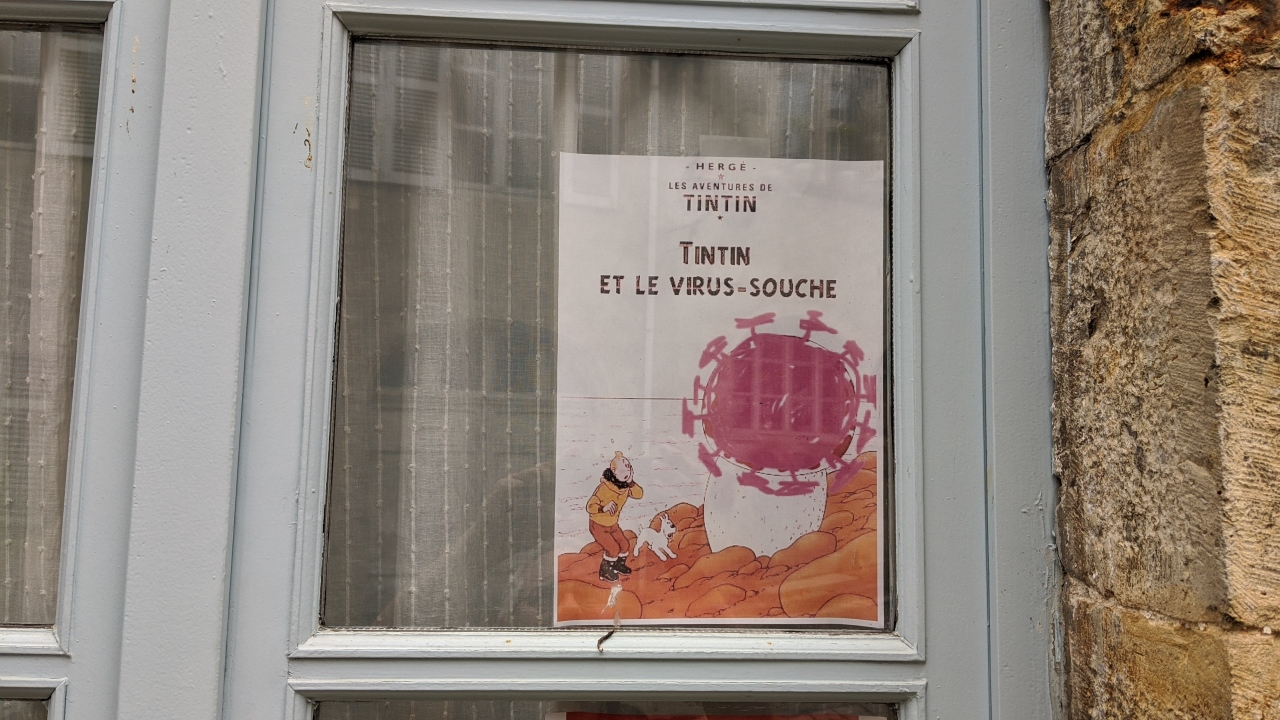 Ein Fenster, was ein abgewandeltes Plakat für Tim und Struppi zeigt. Tintin, das ist der französische Name für Tim und Struppi, betrachtet ein Corona Virus.  