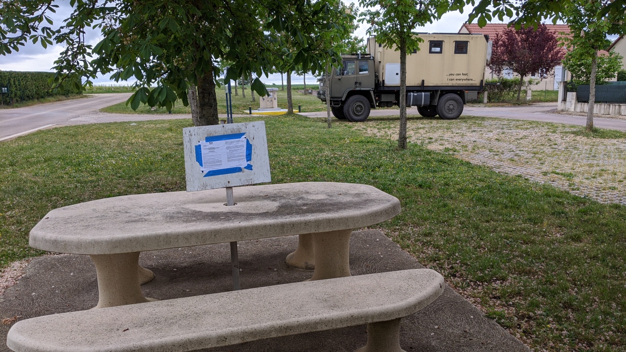 Ein Rastplatz mit Sitzmöglichkeit, dieser ist für die Benutzung wegen Corona gesperrt, worauf ein Schild hinweist. Im Hintergrund ist ein DAF T244 LKW. 