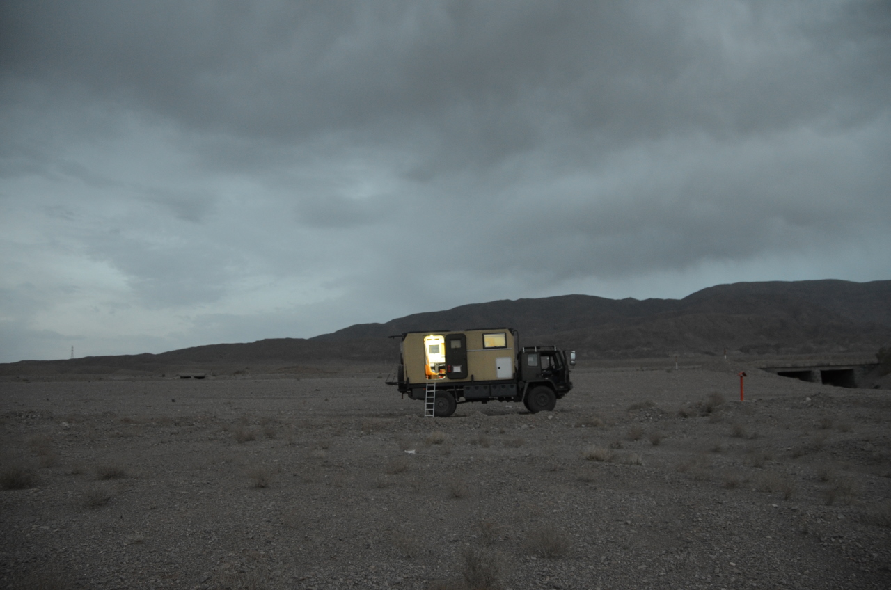 Ein hell erleuchtetes Fahrzeug steht im Hintergrund einer dunklen Landschaft mit dunklen Wolken