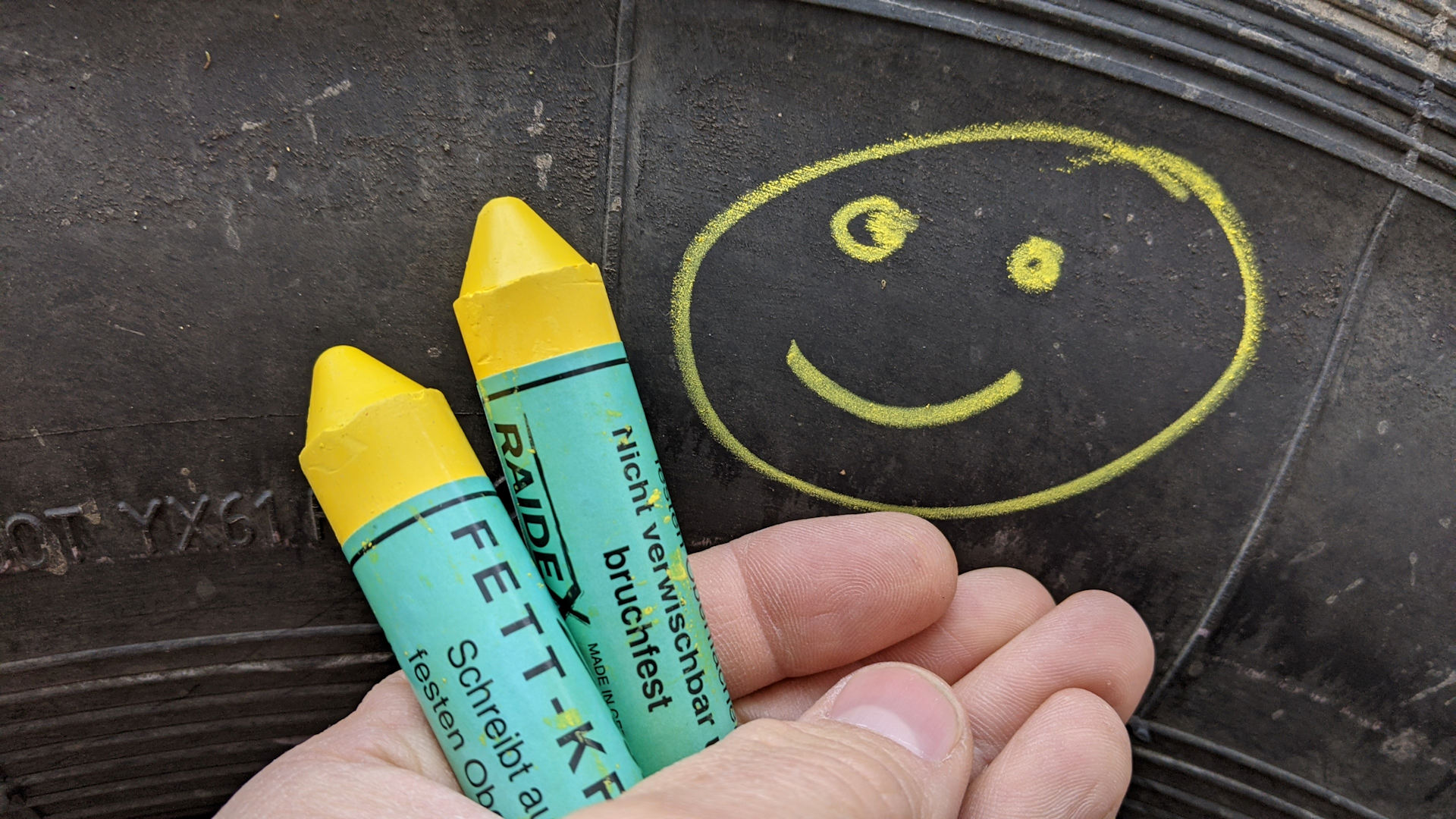 Smilie der mit gelber Fettkreide auf einen Reifen gemalt wurde