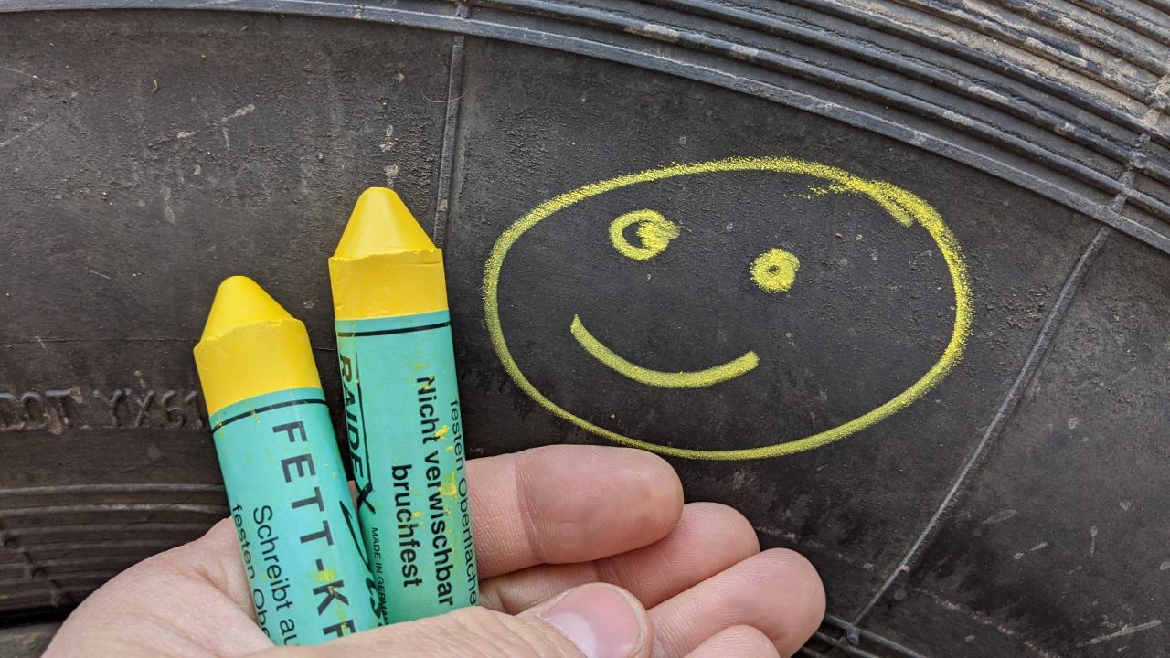 Smilie der mit gelber Fettkreide auf einen Reifen gemalt wurde