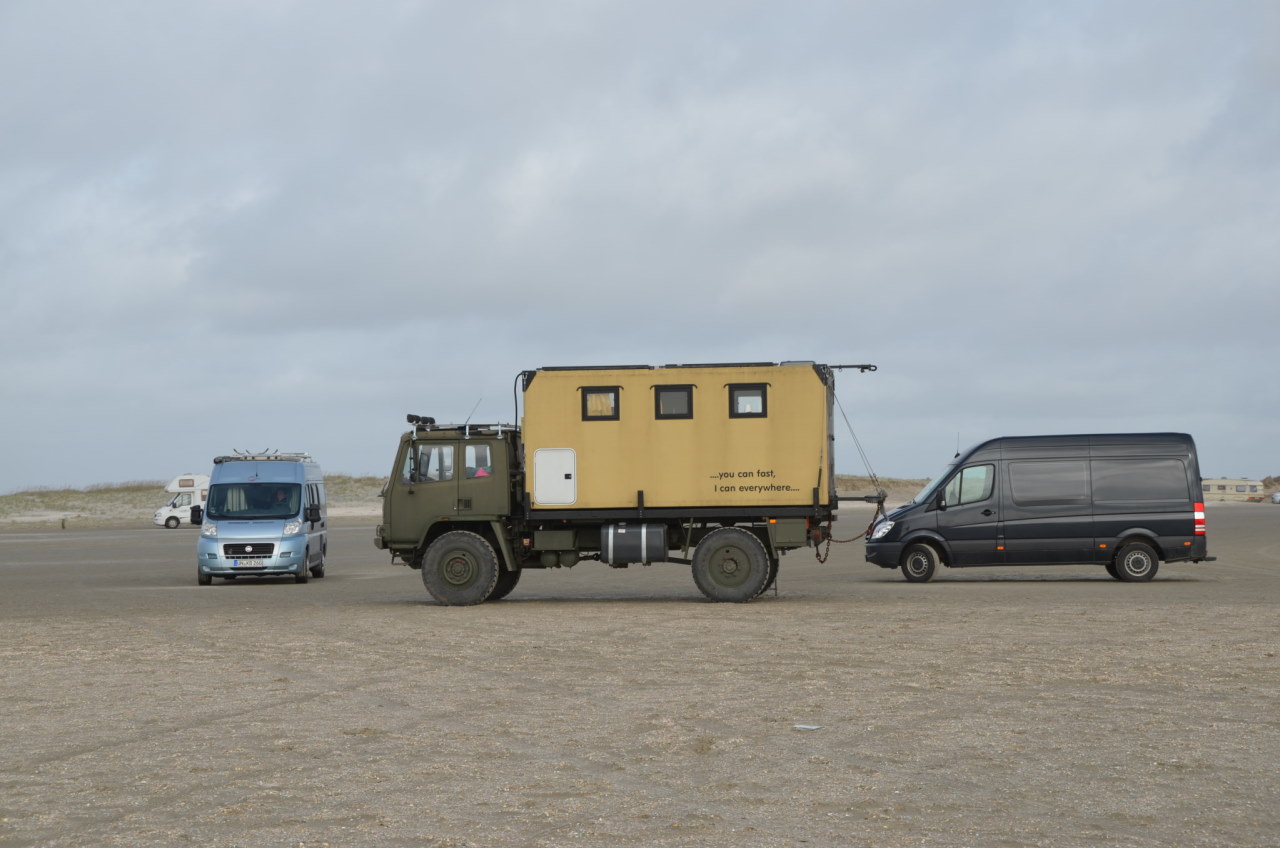 Ein DAF T244 und drei weitere Kastenwagen und Camper am Strand von Dänemark. 