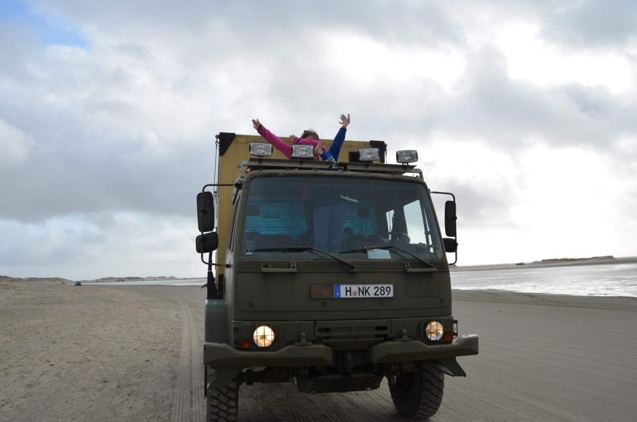 Frontansicht DAF T244 am Strand von Dänemark. Zwei Kinder strecken die Hände aus der Dachluke. 
