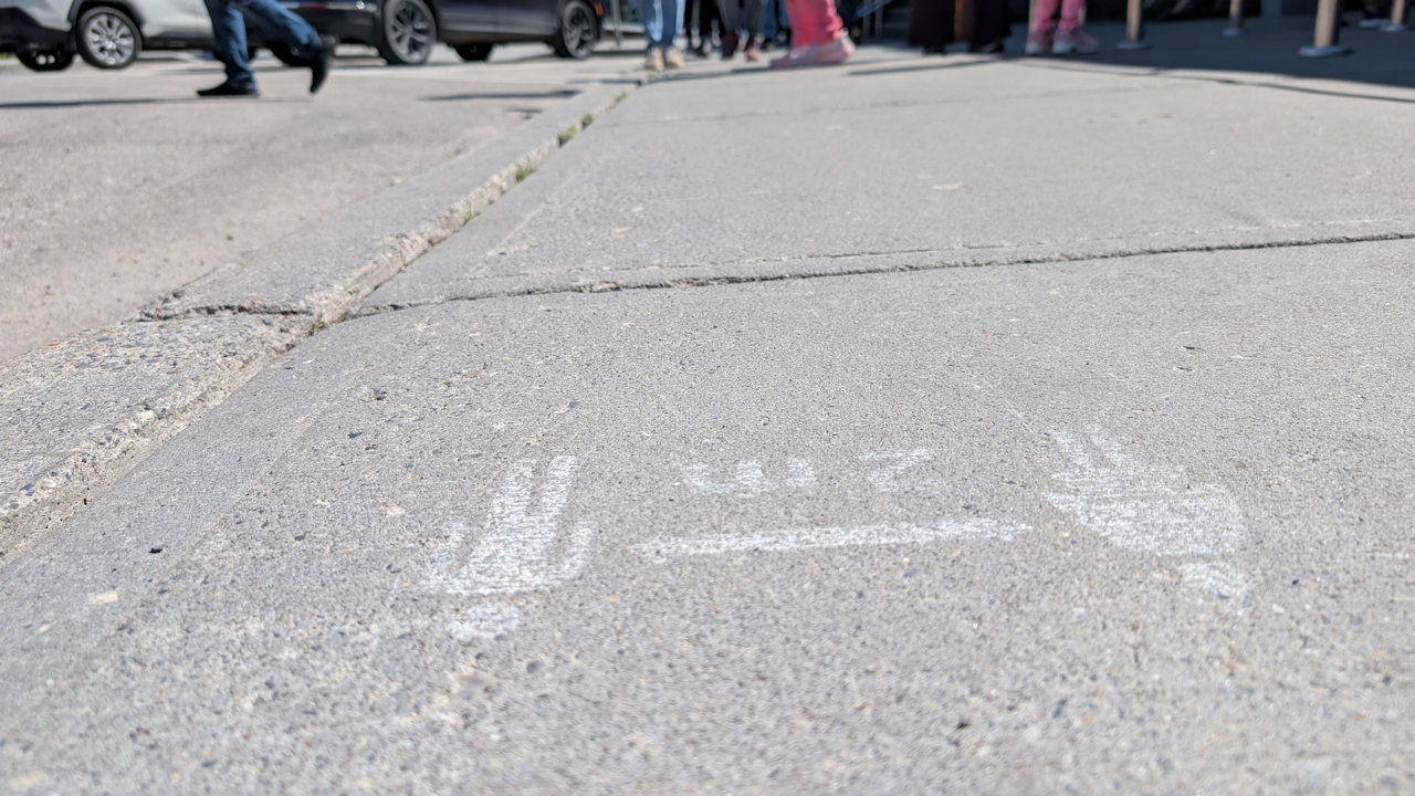 völlig verblasster und abgenutzter "2m Distanz wahren" Hinweis auf einem Bürgersteig