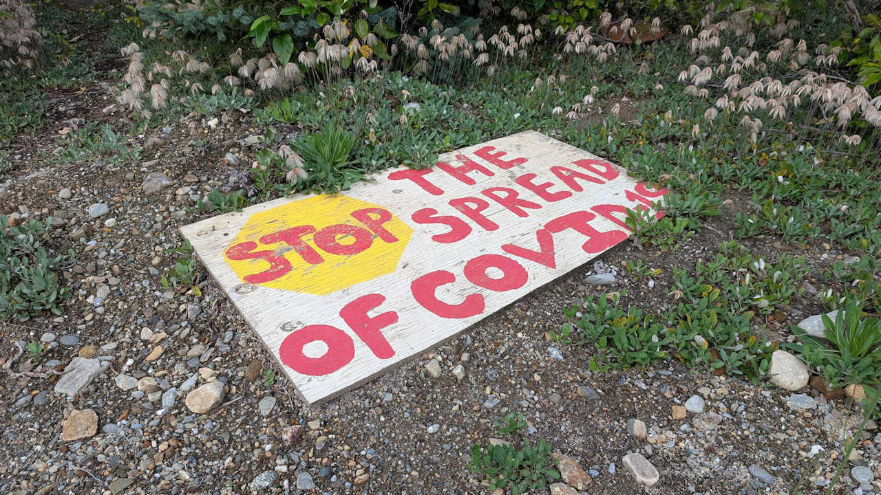 Vergessenen Schild mit Stop the spread of covid19 im Gras 