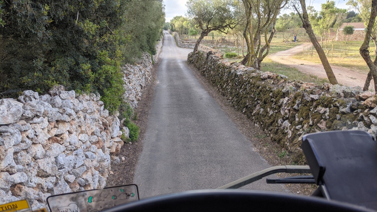 Blick aus dem LKW Cockpit auf eine sehr enge Strasse auf Menorca. Die kleine Strasse ist links und rechts durch eine Mauer aus Felsen begrenzt