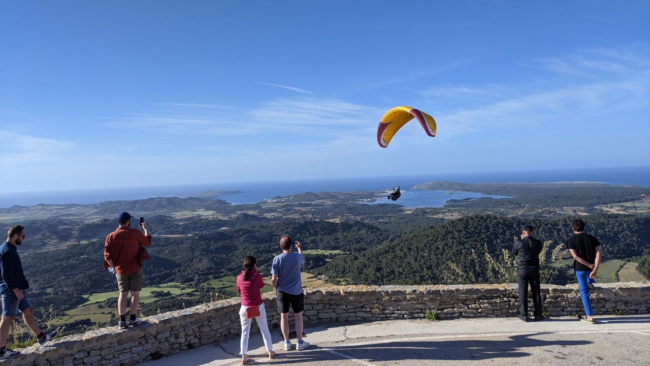 Menschen beobachten einen Gleitschirmflieger Paraglider auf dem Berg del Toro auf Menorca