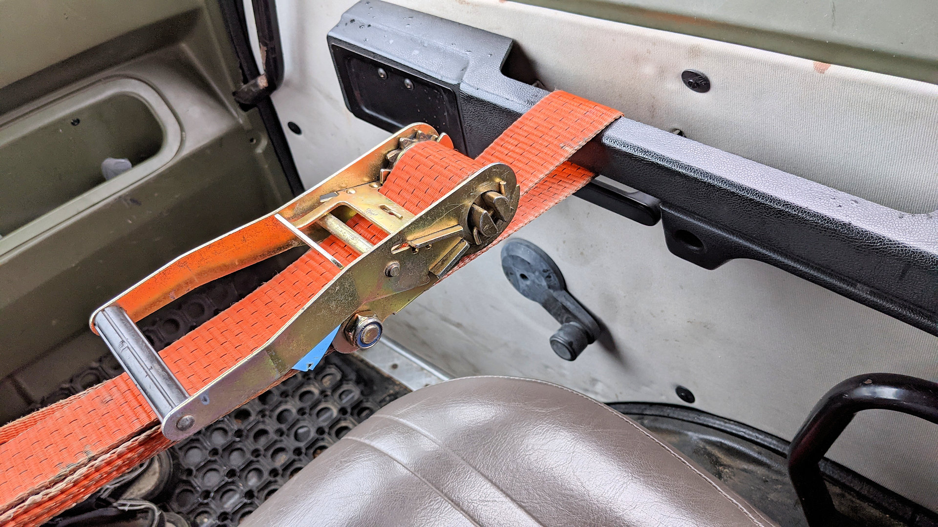 Ein orangener LKW Spanngurt sichert eine LKW Tür von innen 