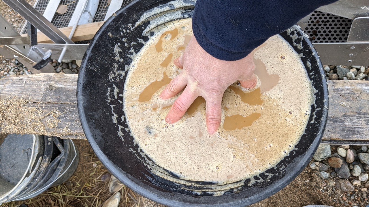 Sand in der Goldwaschpfanne wird durchgemischt