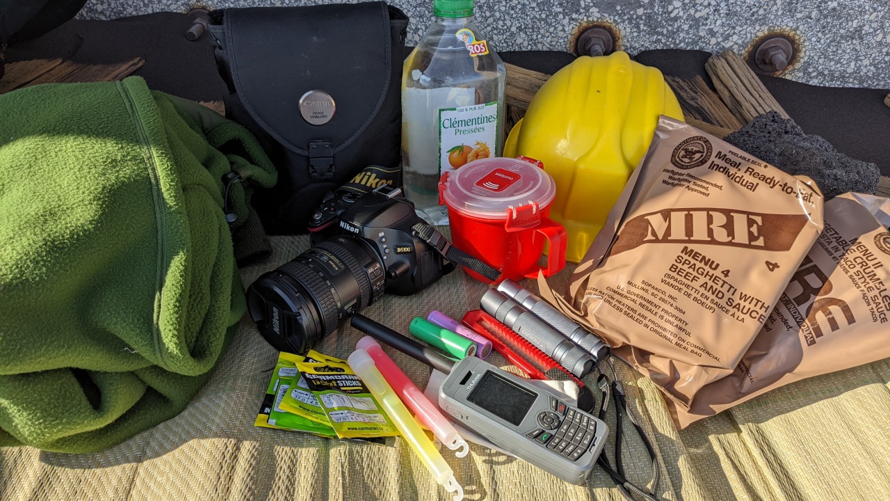 Ausrückstung bestehend aus MRE, warmer Weste, Kamera, taschenlampen, Satelliten Telefon, Becher, Knicklichtern, Wasserflasche, Fernglas und gelben Helm