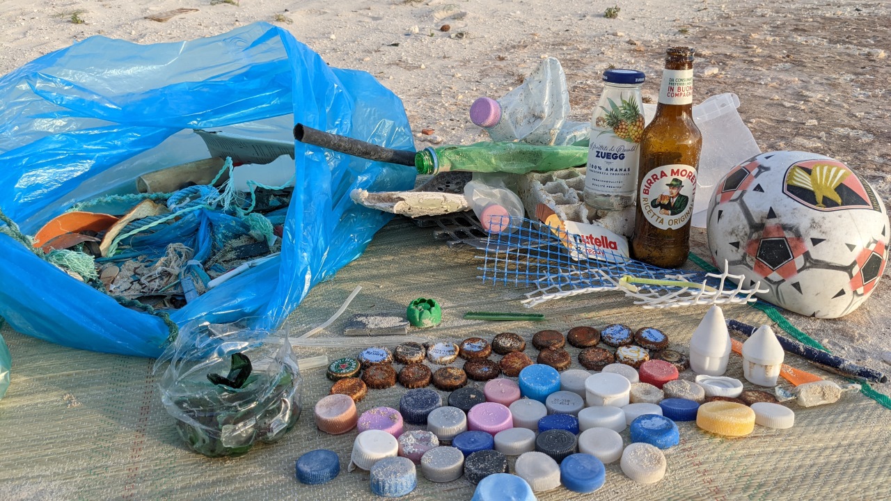 Am Strand gefundener Müll: Flaschenverschlüsse, Glasscherben, Flaschen, kaputter Ball, Plastiklatschen, Seil Reste, PET Flaschen