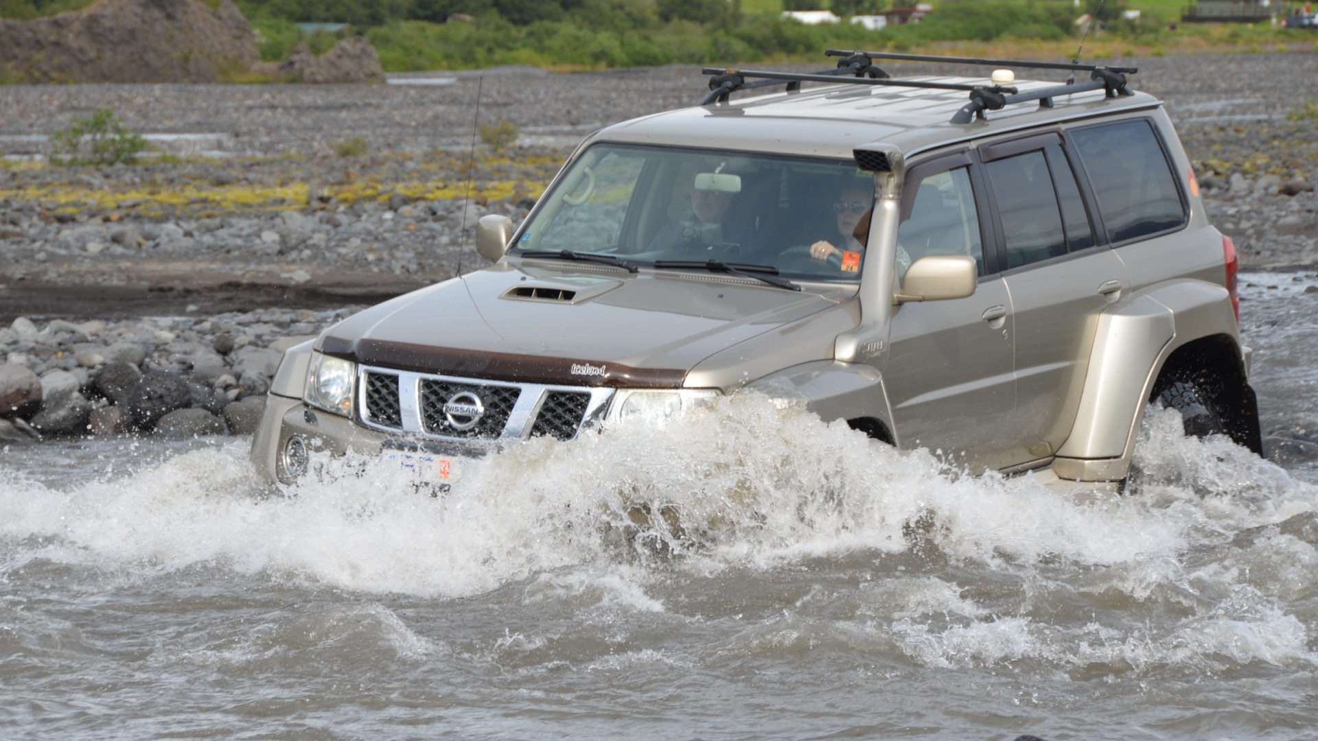 Nissan Patrol 4x4 Geländewagen pflügt in Island durch eine tiefe Furt wobei das Wasser fast die Motorhaube erreicht