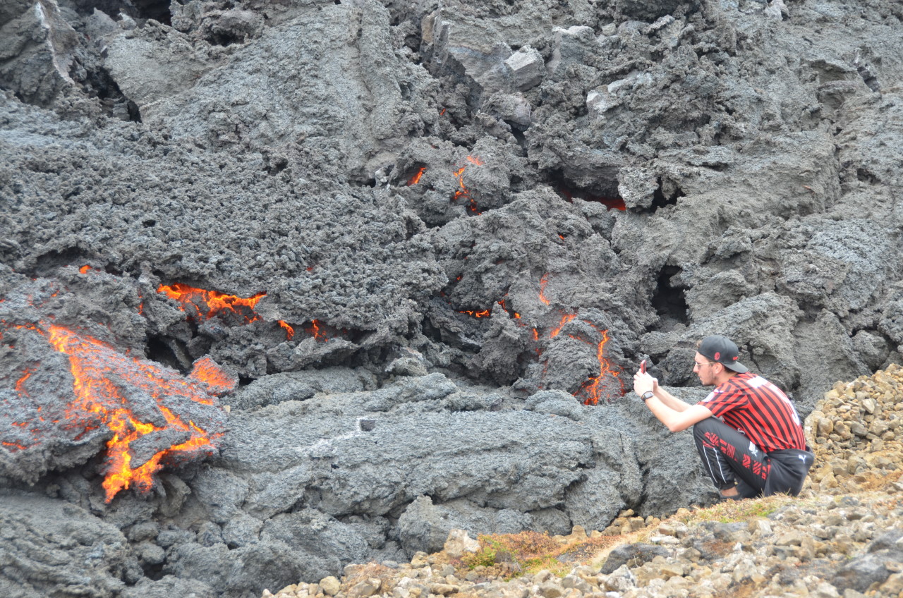 Ein Tourist fotografiert glühende Lava Vulkan in Island