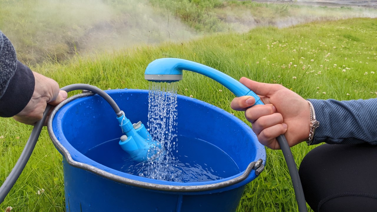 Verwendung einer Akkubrause in einem blauen Eimer Waser. 