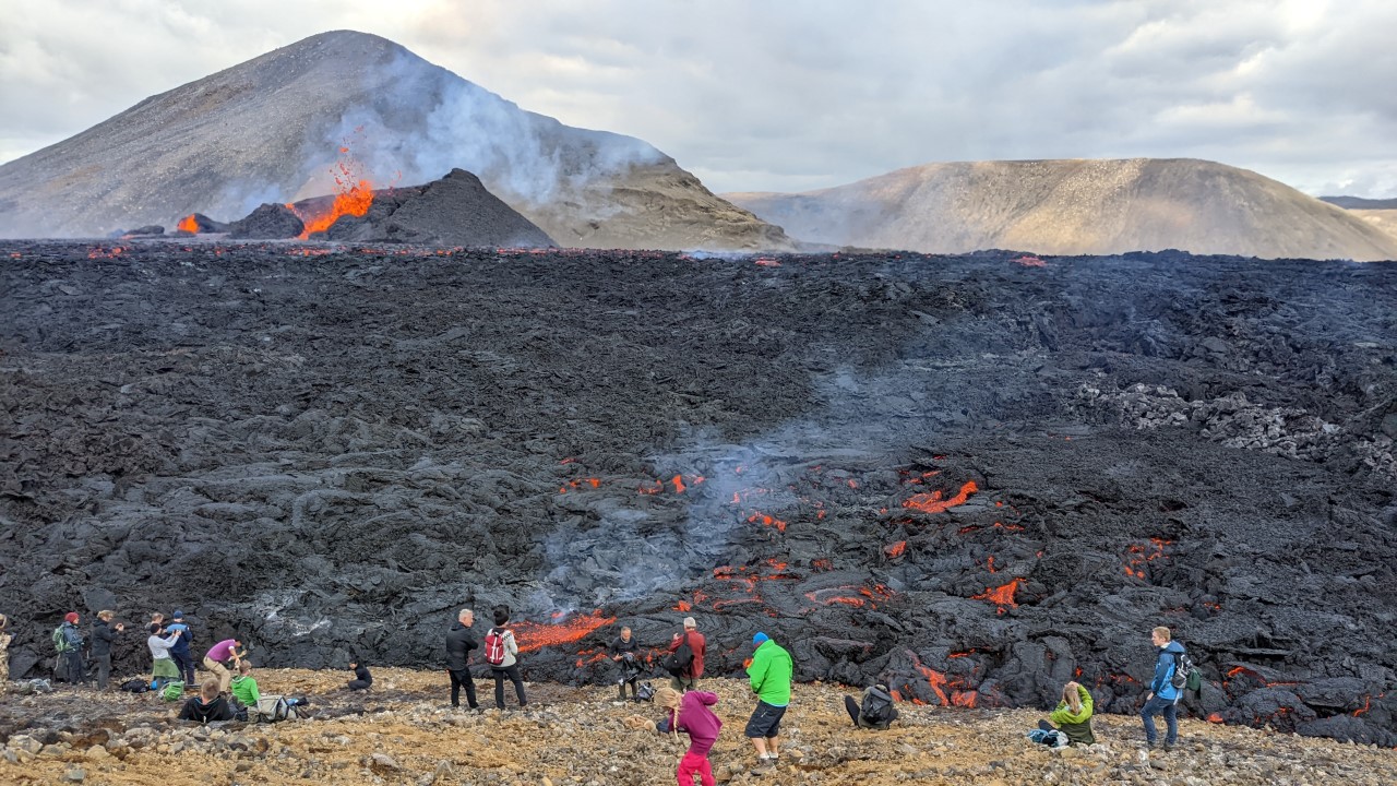 Meradalir Vulkan Kegel mit bunt gekleideten Besuchern im Vordergrund Island 2022