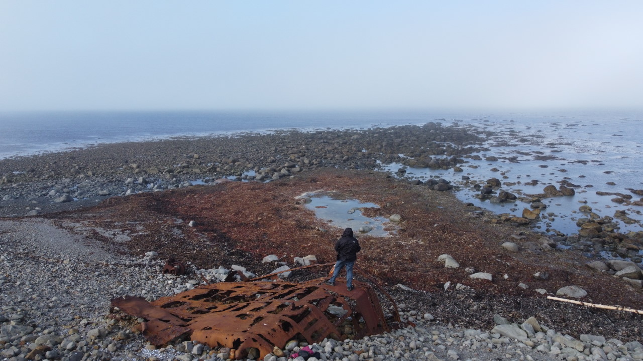 Rifstangi Landzunge Island. Ein Mann steht auf einem Schiffswrack und blickt Richtung Norden aufs Meer