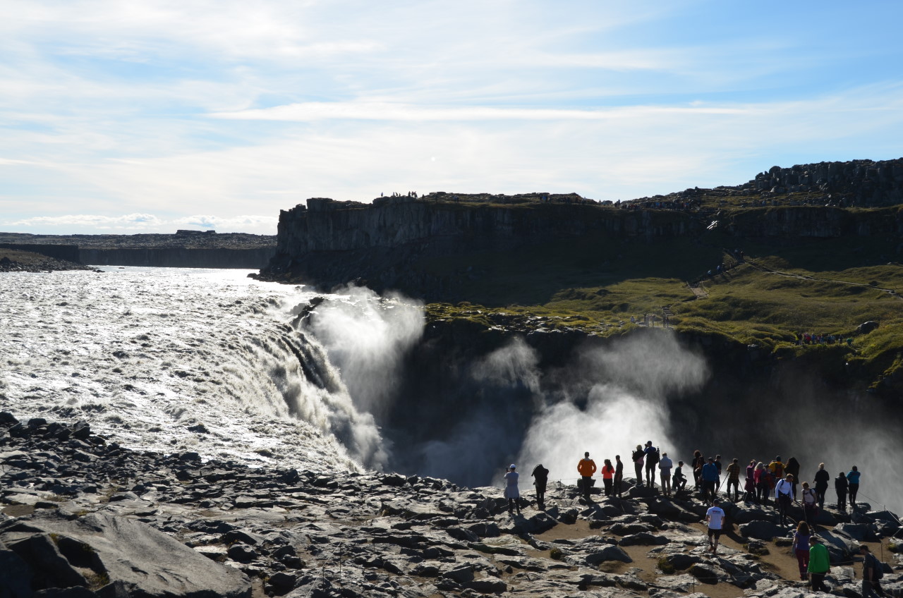 Eine Gruppe von Menschen beobachtet den Dettifoss Wasserfall in Island. 