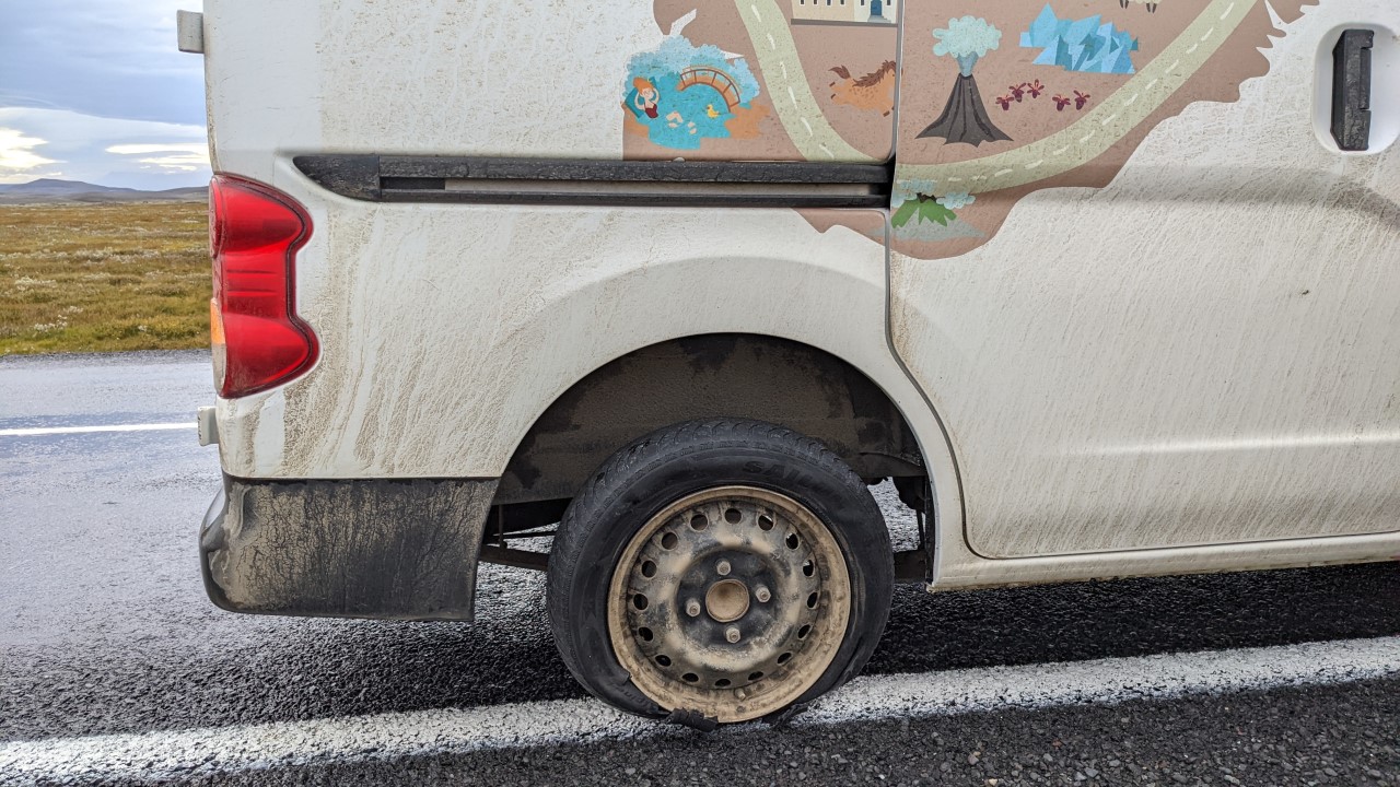 Ein weisser Van steht mit geplatztem Reifen am Strassenrand