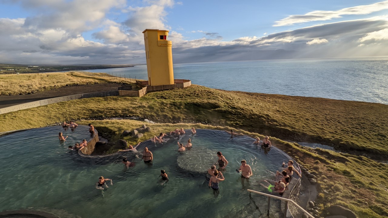 Menschen baden in Geosea Thermalbad in Husavik mit Blick auf das Meer. 