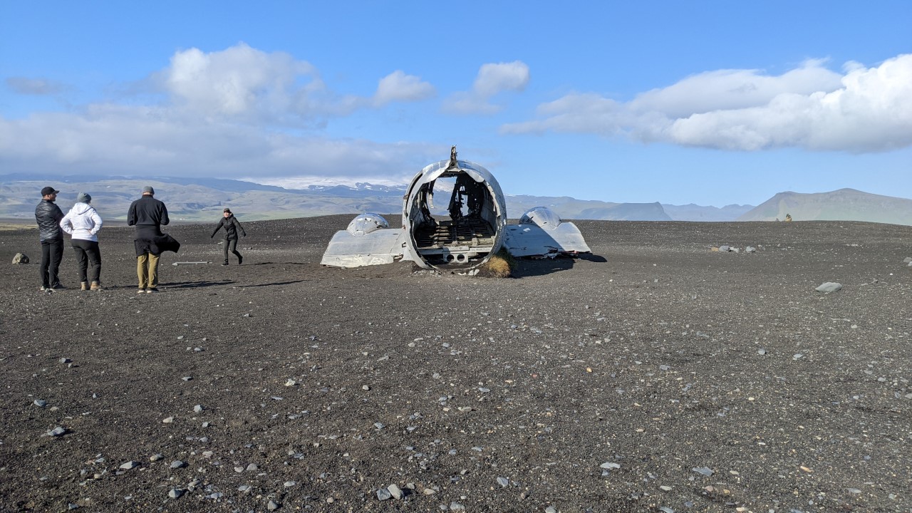 Rest von einem Flugzeugwrack am Südstrand von Island mit vier Touristen. 