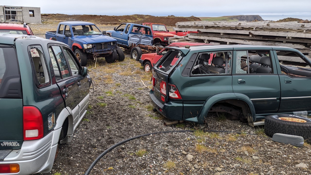 Schrottplatz in Island mit aufgegebenen Fahrzeugwracks ohne Reifen und mit zerstörten Fensterscheiben