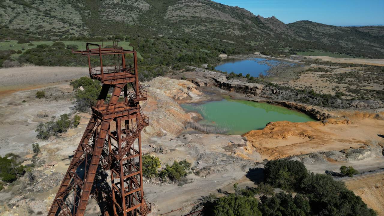 rostiger Förderturm der Monteveccio Mine Sardinien mit Absetzbecken im Hintergrund