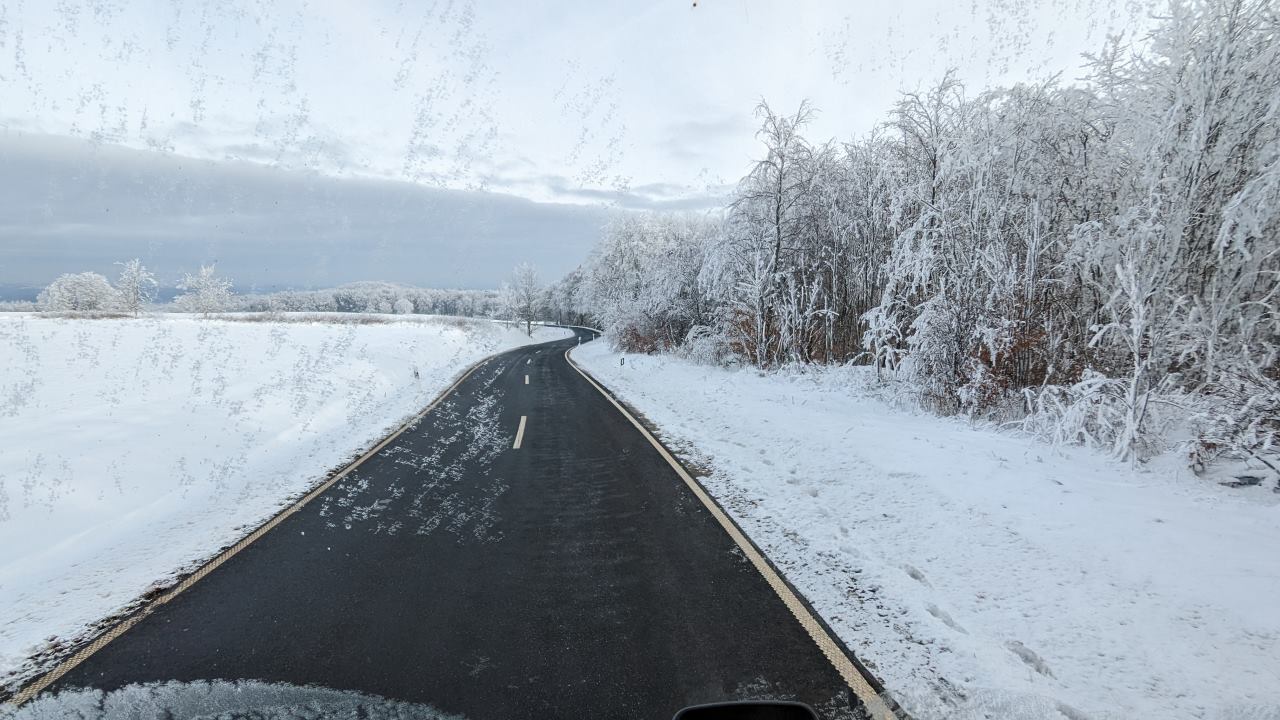 Schwarze Asphalt Strasse in einer Schneebedeckten Landschaft