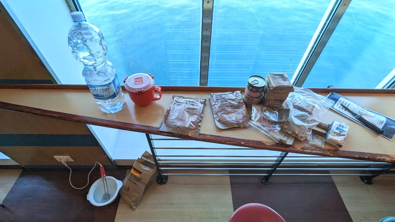Ausgepackte Nahrungs Rationen aus einem Bundeswehr EPA auf einem Tisch an Board der Moby Aki Fähre. Blaues Meer in Hintergrund. 