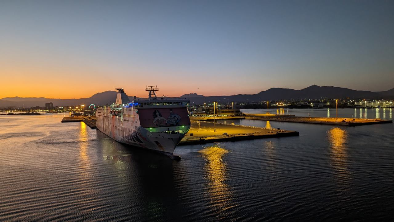 Hafen Olbia, Sonnenuntergang. Die gelbe Hafenbeleuchtung spiegelt sich im Wasser. 