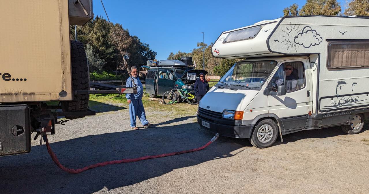 Ein weisses Campingfahrzeug wird für das ziehen mit einem roten Abschleppseil vorbereitet