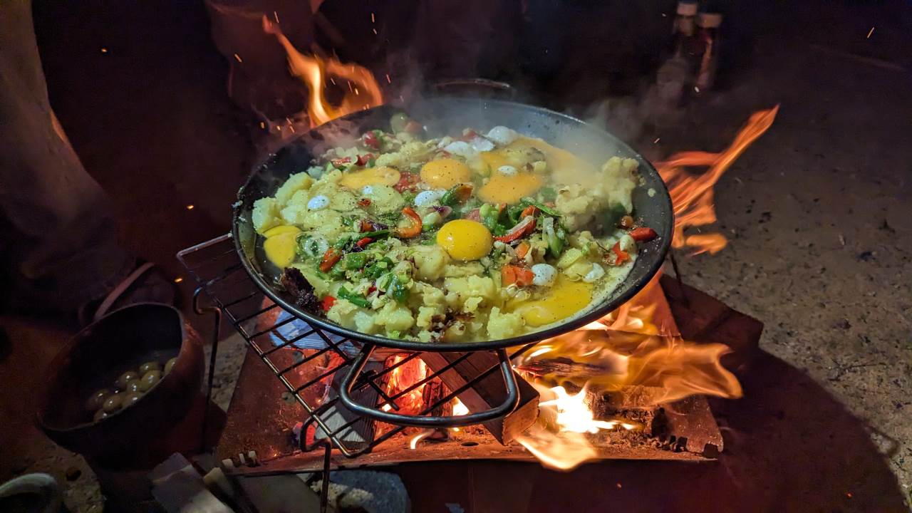 Bratkartoffeln mit Ei in einer Pfanne auf einem Holzfeuer