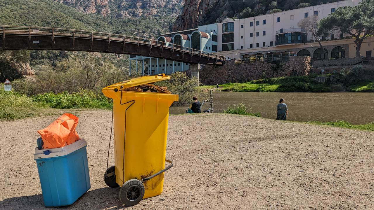 Eine gelbe mit Abfall gefüllte Mülltonne steht an der Casteldoria Thermalquelle zum Abtransport bereit