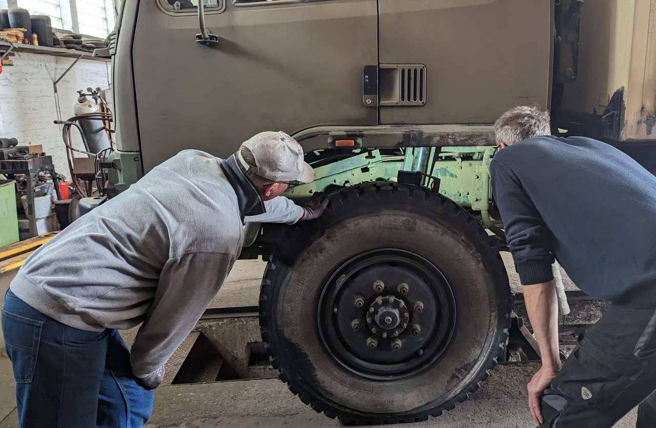 Zwei Mechaniker begutachten in der Werkstatt von Henning Autofedern Hannover ein Fahrzeug. 