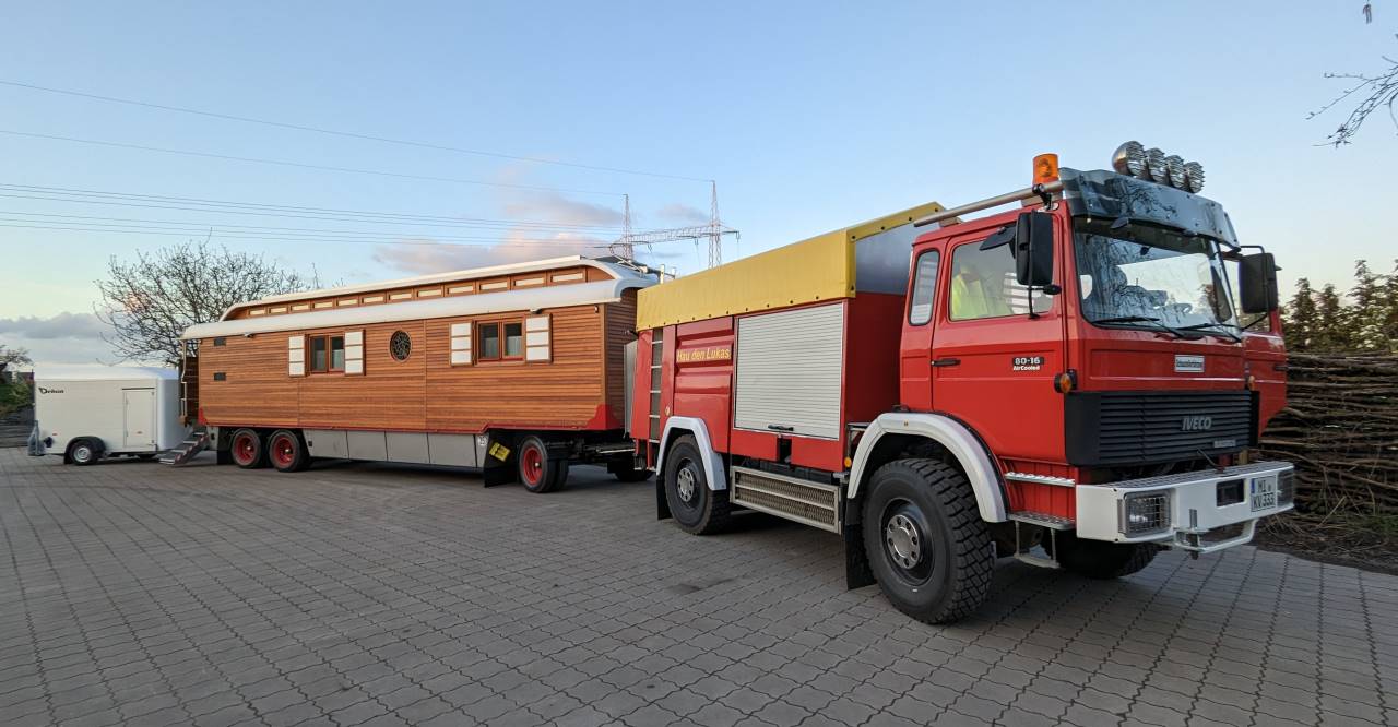 Ein Zirkuswagen Gespann aus Holz mit rotem Iveco LKW