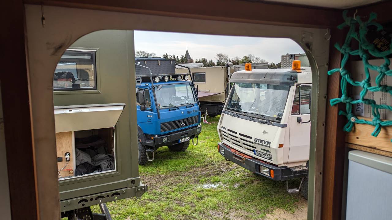 Blich durch die Kabinentür auf einen blauen Mercedes LKW und einen weissen Steyr LKW