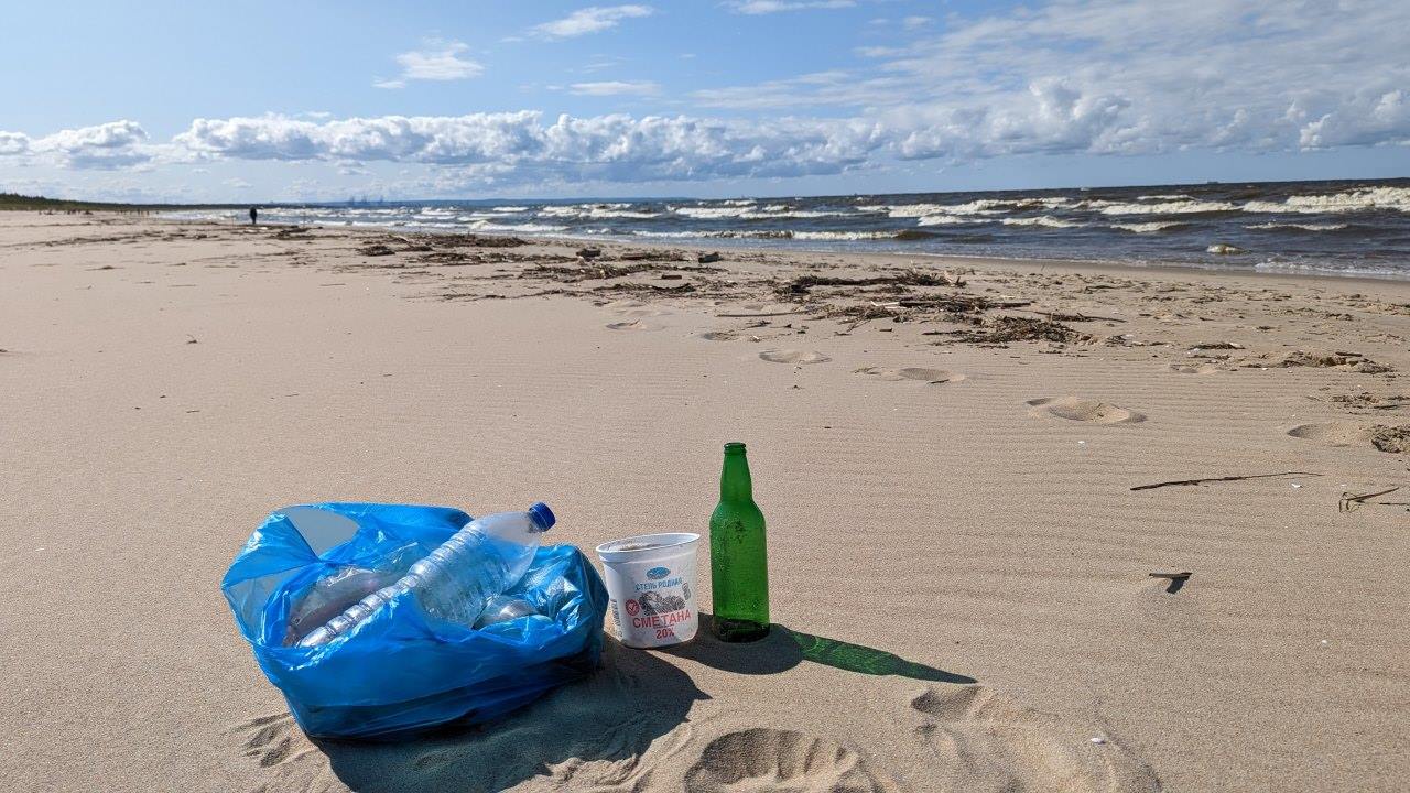 Eine blaue Tüte mit eingesammelten Plastikabfällen am Sand Strand von Sobieszwska in Polen