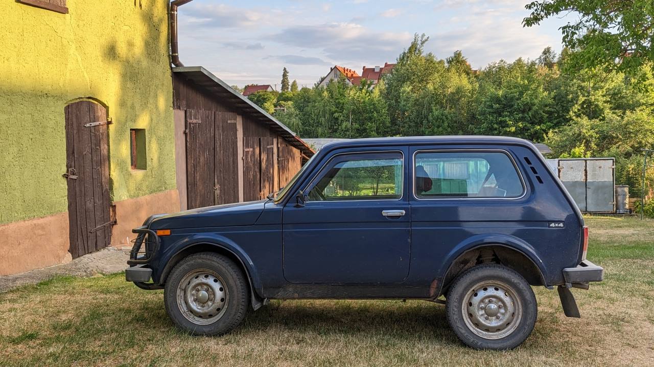 Dunkelblauer Lada 4x4 vor einem grünen Scheinentor