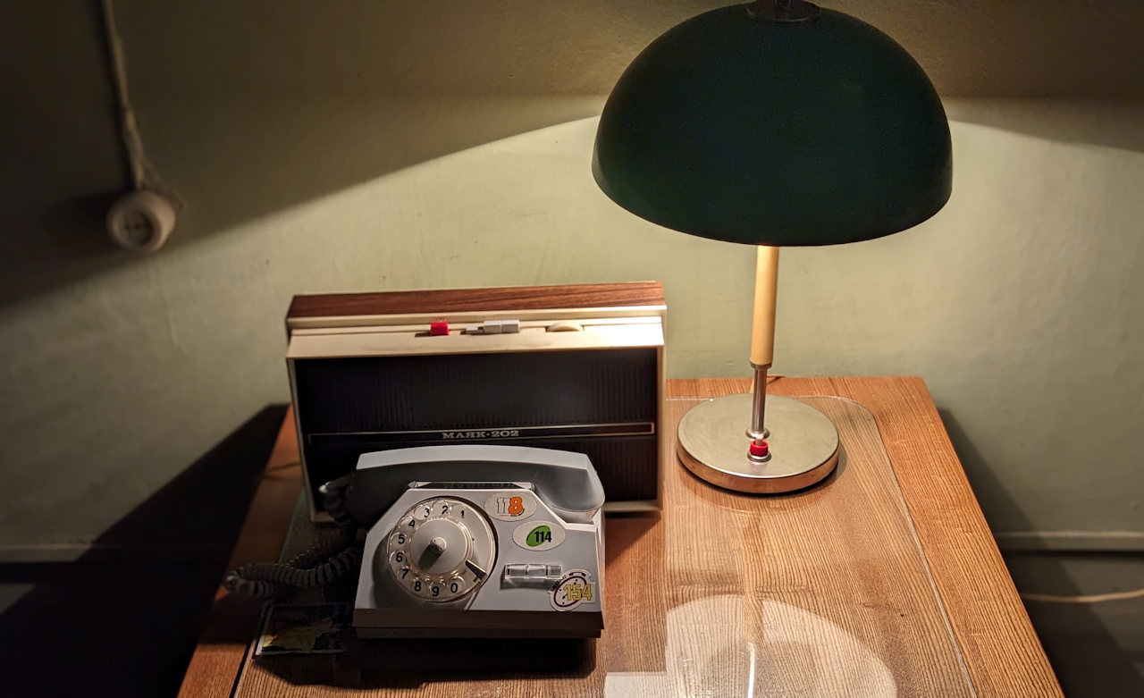 Ein Schreibtisch mit Telefon und Radio wird von einer Schreibtischlampe erleuchtet