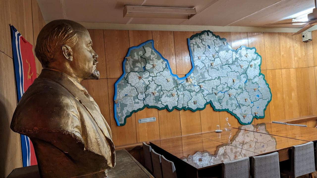 Bestrechungsraum im Bunker Ligatne mit Landkarte an der Wand, Tisch und Stühlen, Lenin Statue