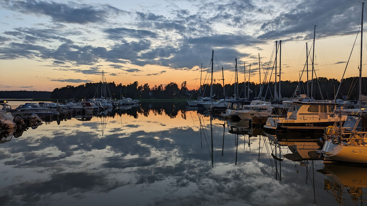 Hafen am Abend, fest liegende Segelschiffe und der Abendhimmel spiegeln sich im glatten Wasser