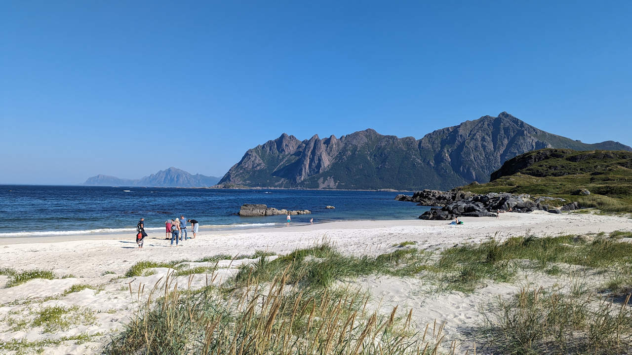 Spaziergänger am Strand von Hovden Norwegen, bei wolkenfreien, blauen Himmel. 