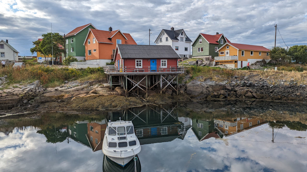 Bunt angemalte Holzhäuser und ein kleines Motorboot in Henningsvaer Lofoten Norwegen