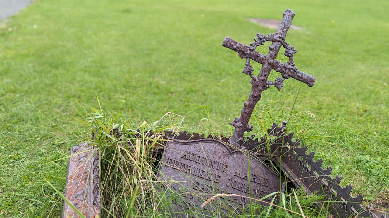 Ein der Erde eingesunkene Grabestelle in Grimsoy Lofoten mit einem rostigen Kreuz 