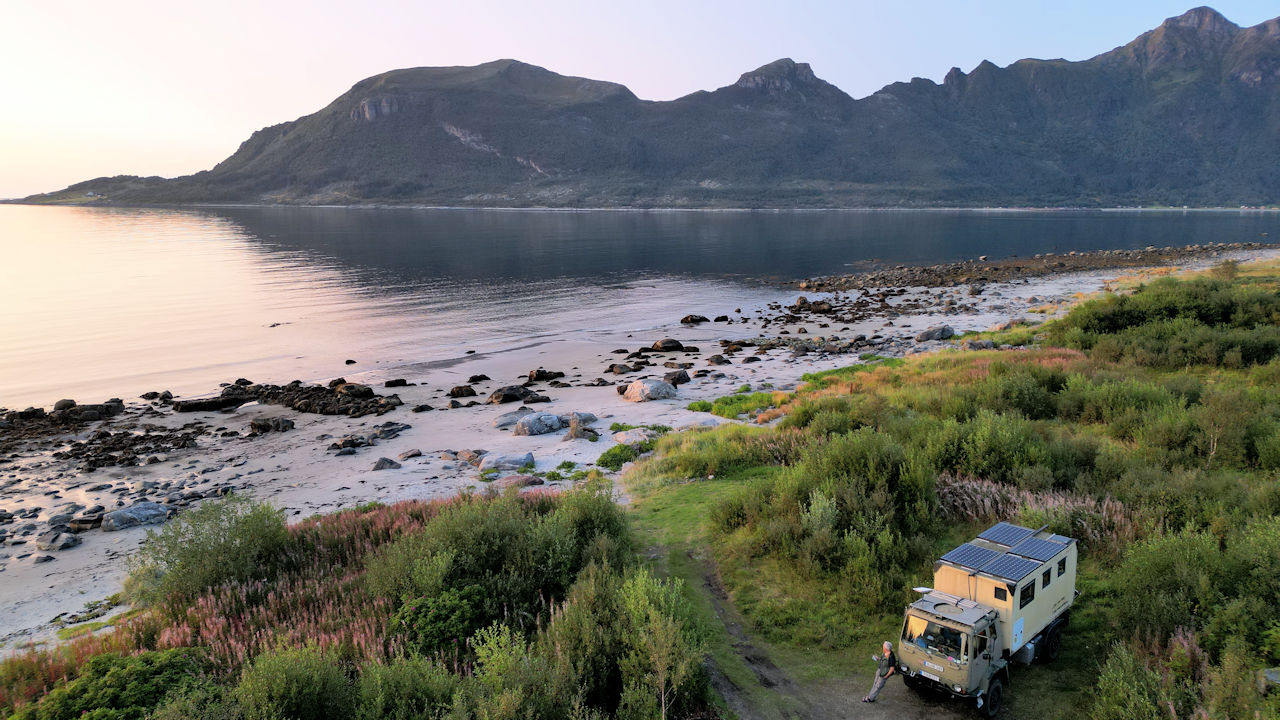 Ein LKW steht in Mevik am Strand mit Blick auf das Meer und die Berge