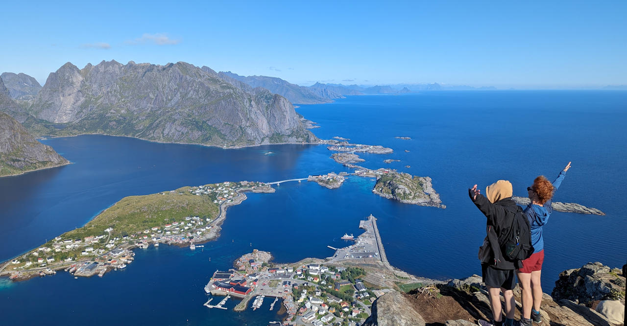 Zwei Touristen blicken vom Reinebringen aus auf die Berge der Lofoten in Norwegen