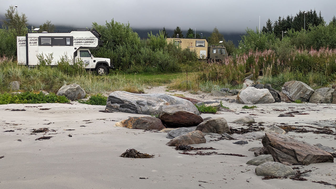 Zwei Campingfahrzeuge mit Starlink Antenne stehen an einem Strand mit Felsen in Norwegen
