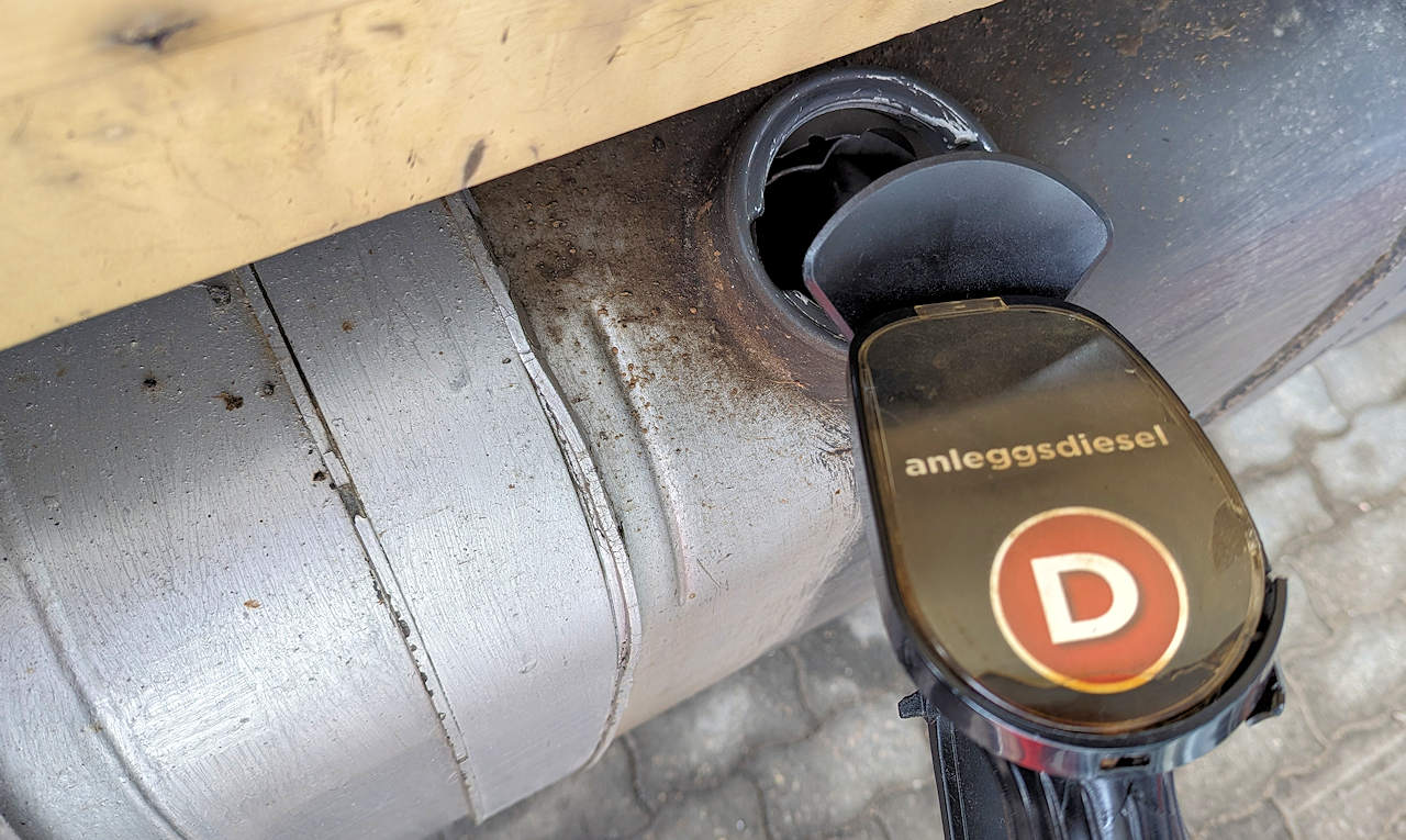 Eine mit anleggsdiesel beschriftete Dieselzapfpistole steckt in einem silbernen LKW Tank