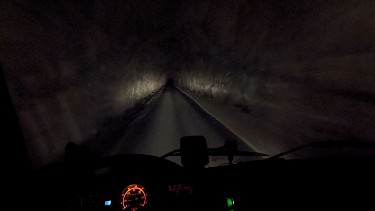 Fahrt in einem unbeleuchteten Tunnel in Norwegen vom Cockpit eines LKW mit spärlicher Instrumentenbeleuchtung aus gesehen. 