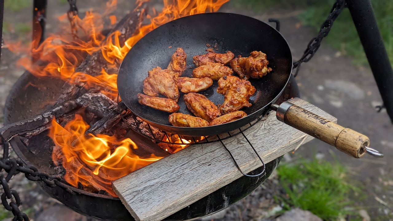 Eine Pfanne mit Hähnchenteilen auf einem Lagerfeuer