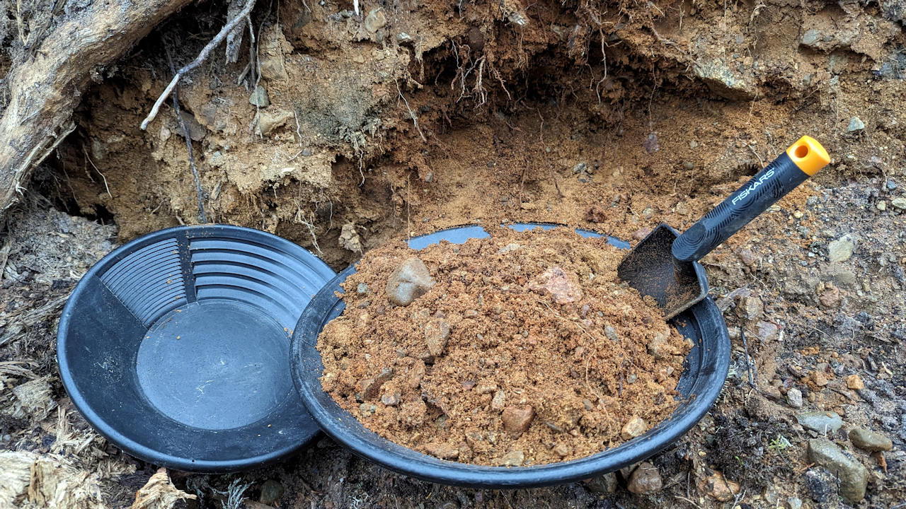 Goldwaschschüssel die mit potentiell goldhaltigem Sand gefüllt ist. 